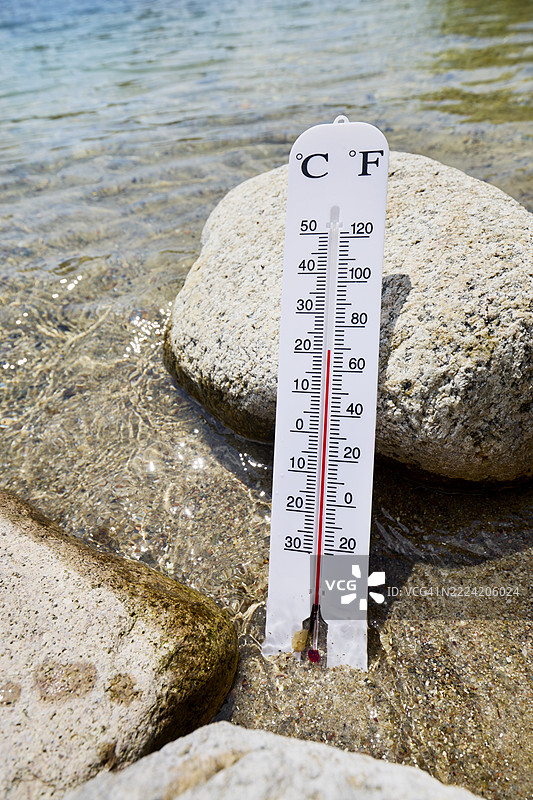 温度计靠在湖边的石头上，测量水温图片素材