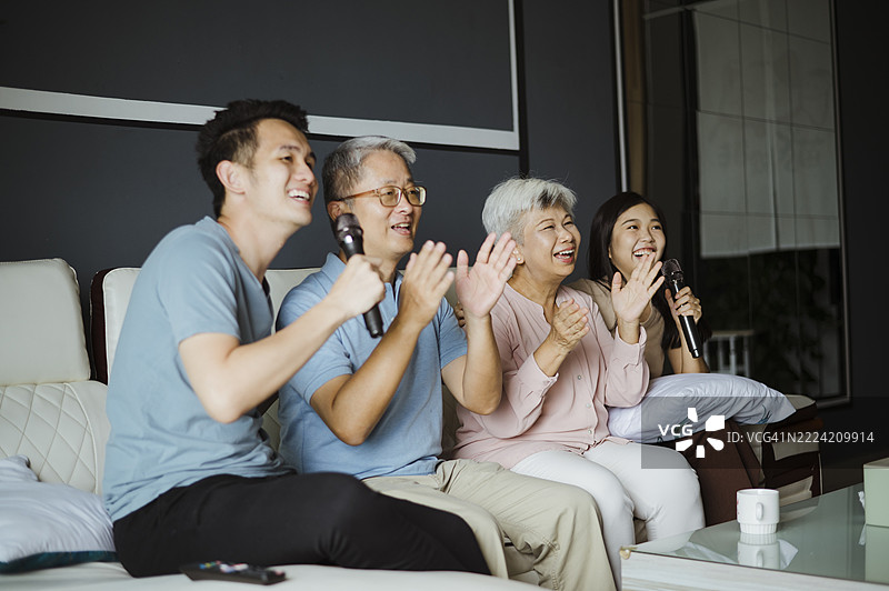 亚洲家庭在周末休闲活动中在家唱卡拉OK。图片素材