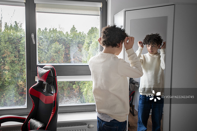 青少年男孩在家镜子前整理头发图片素材