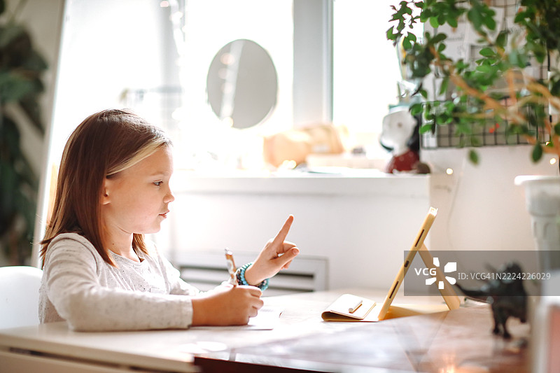 在家教育：小女孩专注地看着平板电脑图片素材