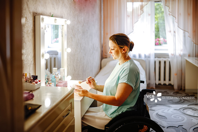 坐在轮椅上的女性在卧室镜子前化妆图片素材
