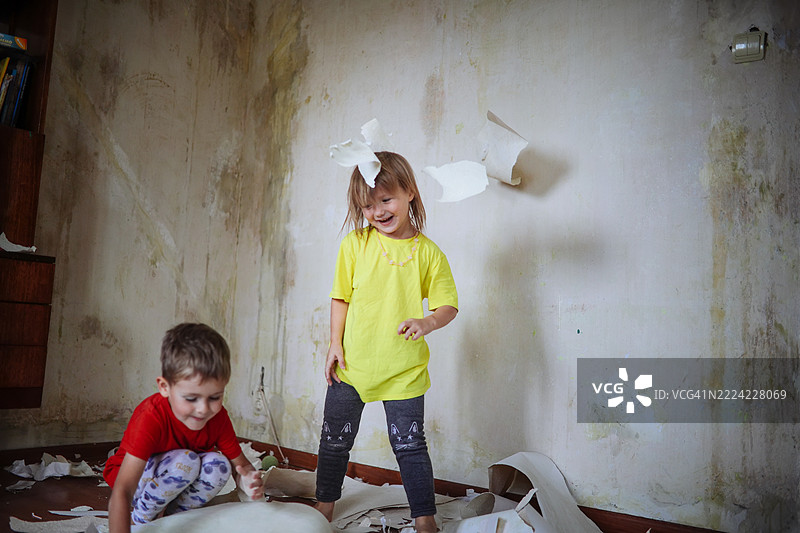 家居的温馨感在兄弟姐妹快乐地玩弄墙纸片的过程中显现出来。图片素材