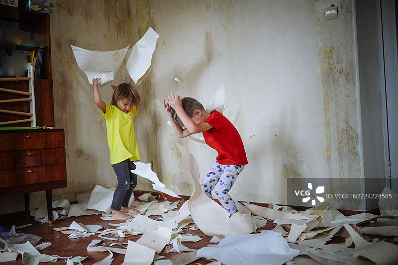 快乐的兄弟姐妹在家居装修期间玩墙纸 scraps，更新房子。图片素材