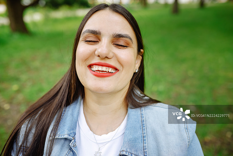 在散步时，坐在轮椅上的棕发女性脸上洋溢着快乐的情感。特写肖像，双眼闭合。图片素材