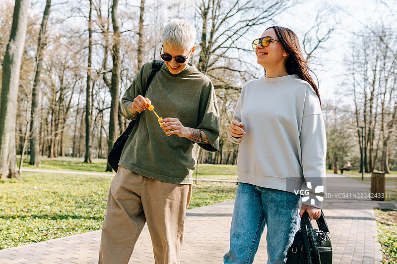 两位年轻女性在公园散步时制作肥皂泡泡图片素材