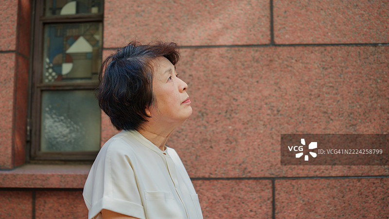 一位年长女性在东京的城市中悠闲地散步，享受她的时光。图片素材