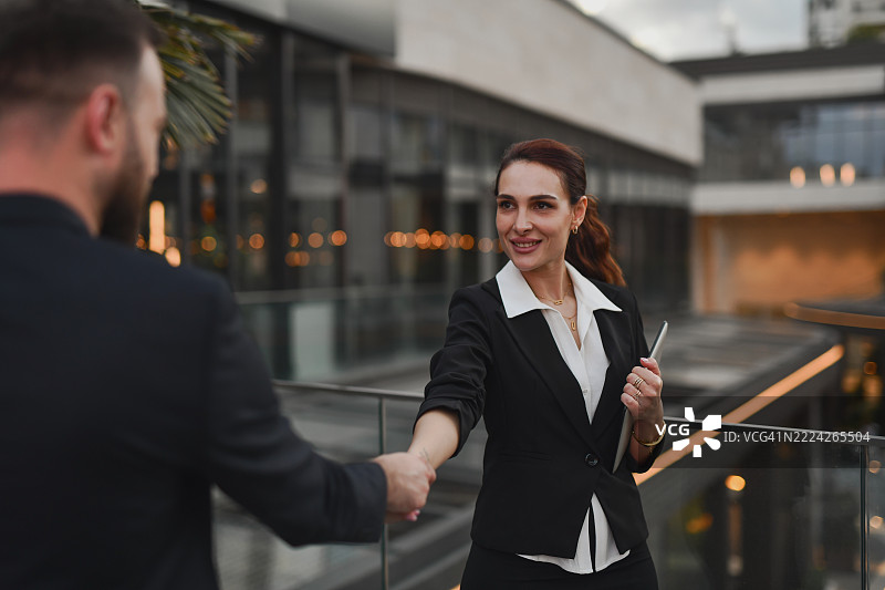 自信的职业女性与男性竞争对手握手图片素材