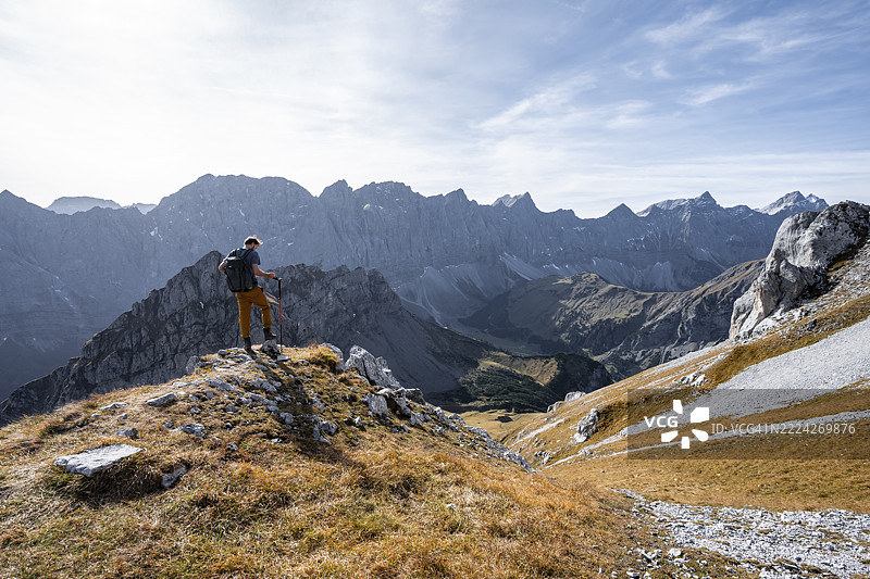 秋季,在奥地利蒂罗尔州卡文德尔山脉的恩格地区,里斯坦谷上方,登山者正从加姆斯约赫(Gamsjoch)下山,身后是欣特劳塔尔-沃姆珀(Hinterautal-Vomper)山脊,构成一幅风景如画的山景全景。图片素材