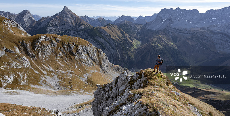 秋季在加姆斯约赫徒步小径上的登山者,风景如画的山地景观,岩石山脊、霍赫格吕克峰、米特斯皮策峰和松恩约赫峰的山峰,恩格的里斯塔尔,卡文德尔,蒂罗尔,奥地利,欧洲图片素材