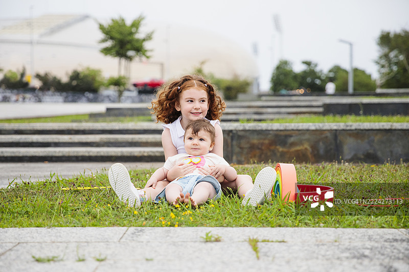 女学生和婴儿在公园里玩木制彩虹玩具图片素材