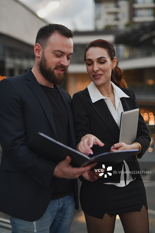 吸引人的专业人士在办公室露台上并肩评估合同草案图片素材