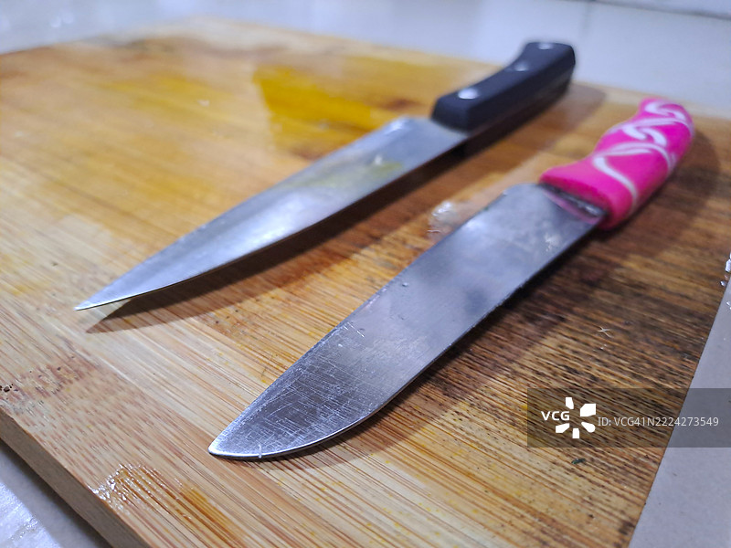 黑色和粉色的厨房刀具放在木质切菜板上图片素材