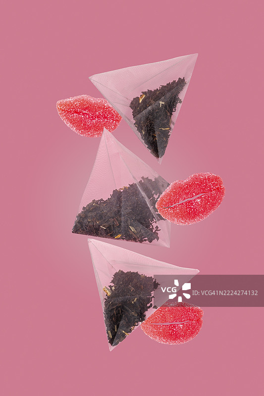 红唇形状的茶包和橘子酱在粉色背景上飞舞图片素材