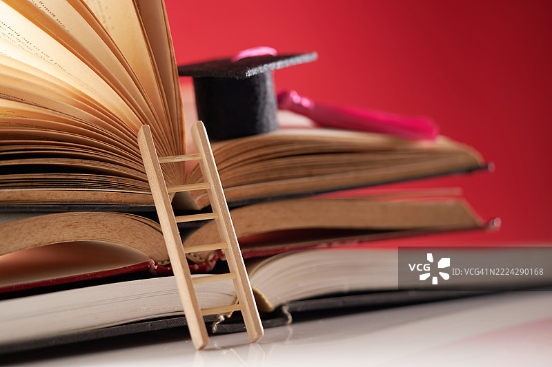 红色背景上的毕业帽、书籍和楼梯，马来西亚图片素材