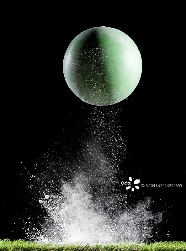 绿色球体在黑色背景下与白色粉末表面碰撞和反弹的效果图片素材