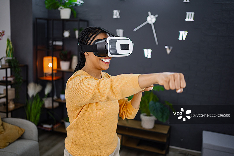 一名女子在家中戴着虚拟现实头显玩拳击游戏图片素材