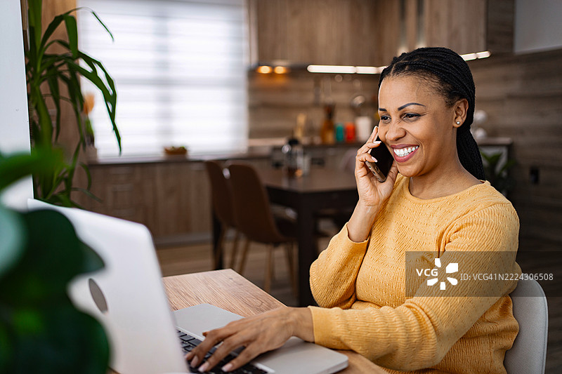 快乐的自由职业者在远程工作，使用笔记本电脑和手机图片素材