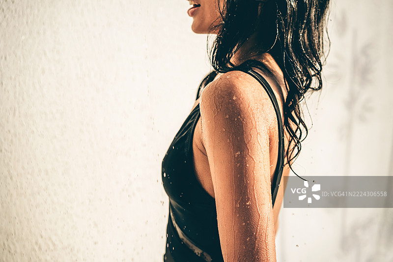 一位美丽的陌生女性在户外淋浴中洗头。图片素材