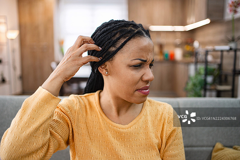 女人抓着头，遭受头发和头皮问题的困扰图片素材
