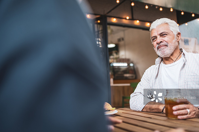 老年人在户外咖啡馆享受饮品和交谈图片素材