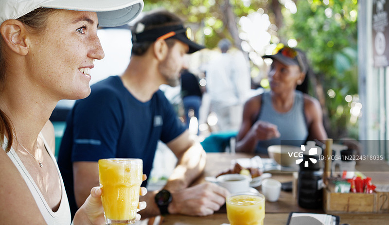 快乐的女性在咖啡桌旁享用橙汁，刚刚参加完团体跑步。图片素材