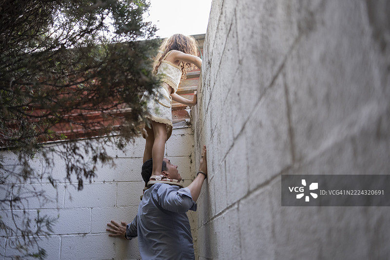 父亲与女儿一起生活，他们在墙边眺望。图片素材