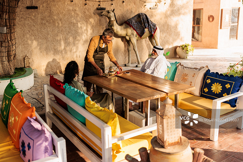 在阿尔法希迪咖啡馆，服务员为顾客送上阿拉伯茶图片素材