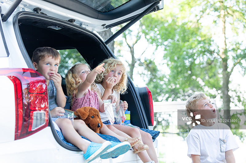 快乐的孩子们在汽车后备厢里享受零食图片素材