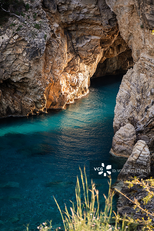 岩石悬崖和植被环绕的洞穴内碧绿色的风景水域图片素材