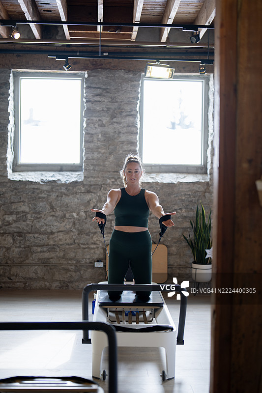 女性在健身工作室的普拉提改革者上锻炼图片素材