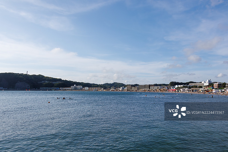 逗子海滩挤满了来自海外的游客。地平线上是江之岛和山的轮廓。这里也是风帆冲浪和立式划水的圣地。一些人在防波堤上钓鱼。图片素材