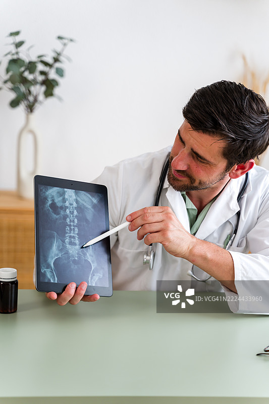 医生在医疗办公室用平板电脑指着数字X光片图片素材