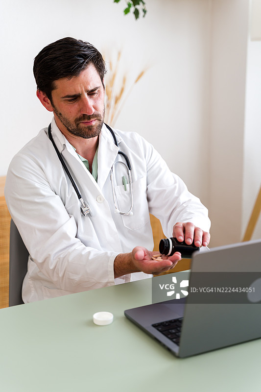 医生在远程医疗咨询中将药丸倒在手上图片素材