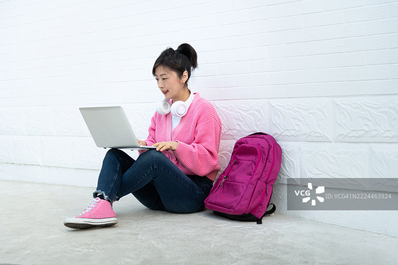 年轻女性坐在地板上使用笔记本电脑图片素材