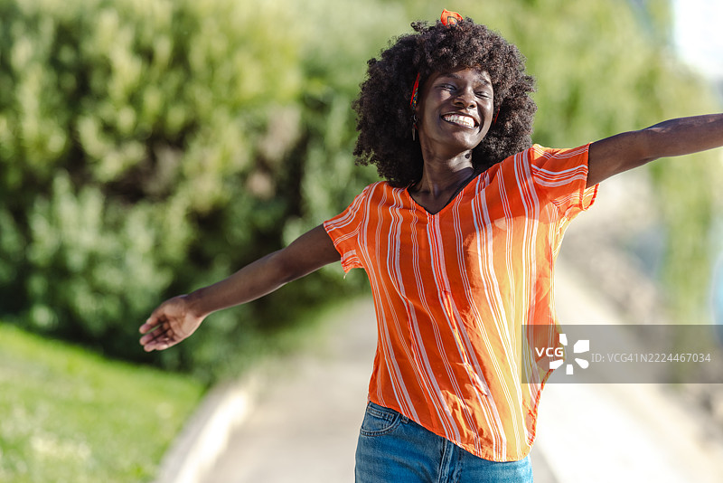 微笑的女性在户外享受阳光明媚的日子，双臂张开。图片素材