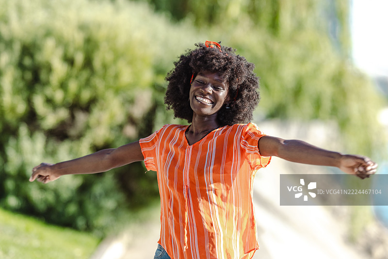 微笑的女性在户外享受阳光明媚的日子，双臂张开。图片素材