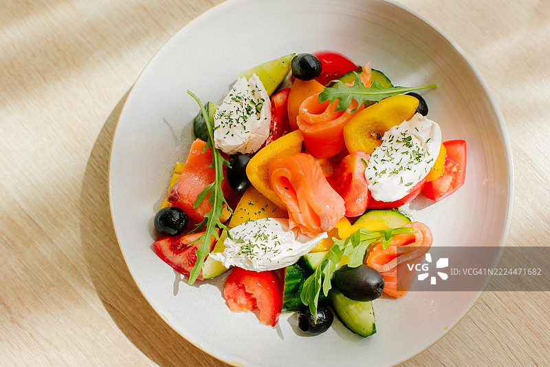 色彩鲜艳的新鲜沙拉菜肴，配有蔬菜和奶油奶酪，盛放在白色盘子上图片素材
