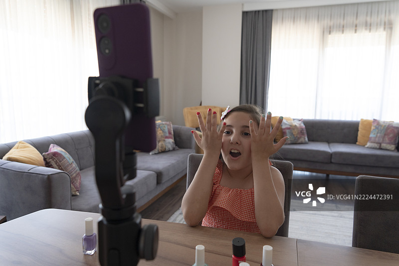 一位才华横溢的年轻女孩正在展示化妆品，同时录制她的化妆教程。图片素材