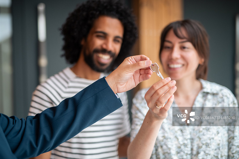 房地产经纪人与快乐的夫妇交接钥匙图片素材