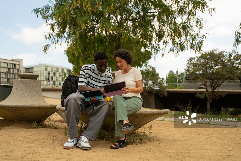 两位年轻人在户外工作空间中使用平板电脑合作图片素材