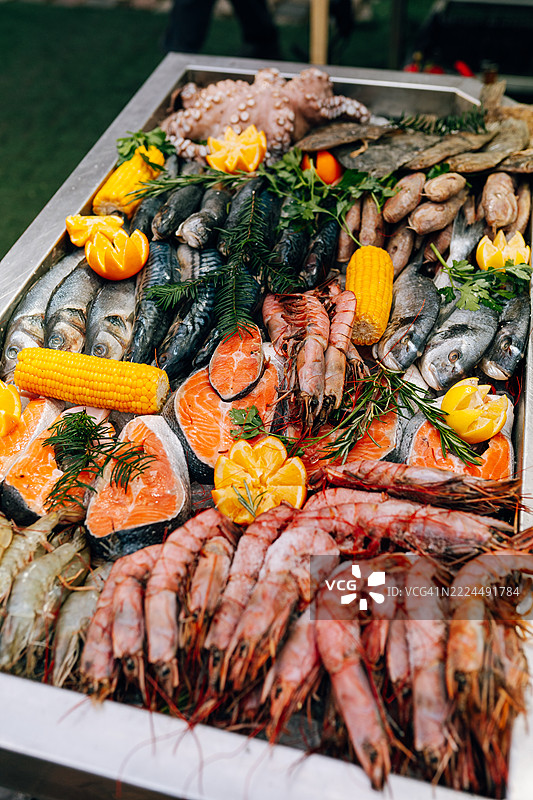 新鲜海鲜在冰上展示，配有香草和柠檬片图片素材