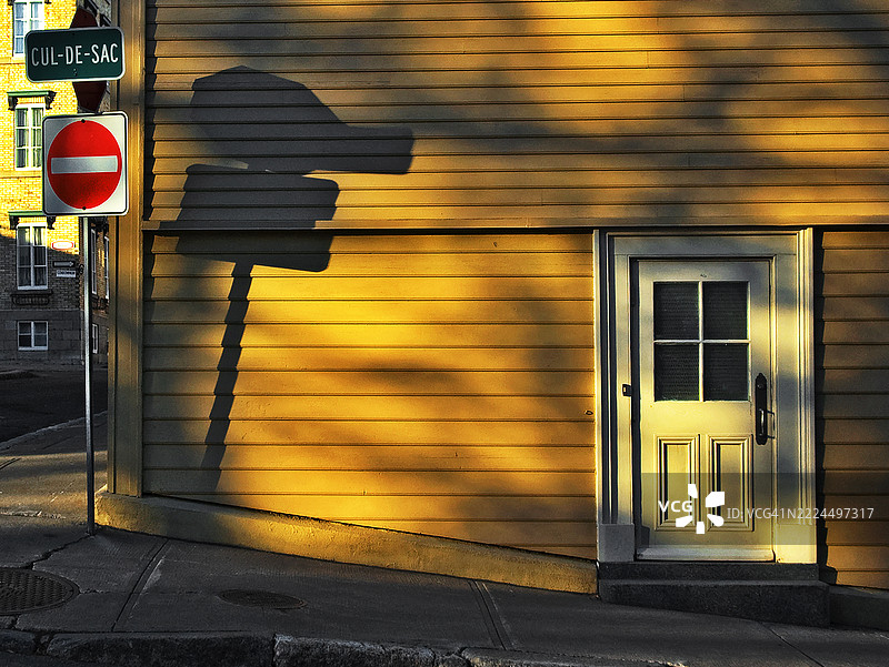 一栋房子的外立面被晨光照亮。一个标志写着“死胡同”。图片素材