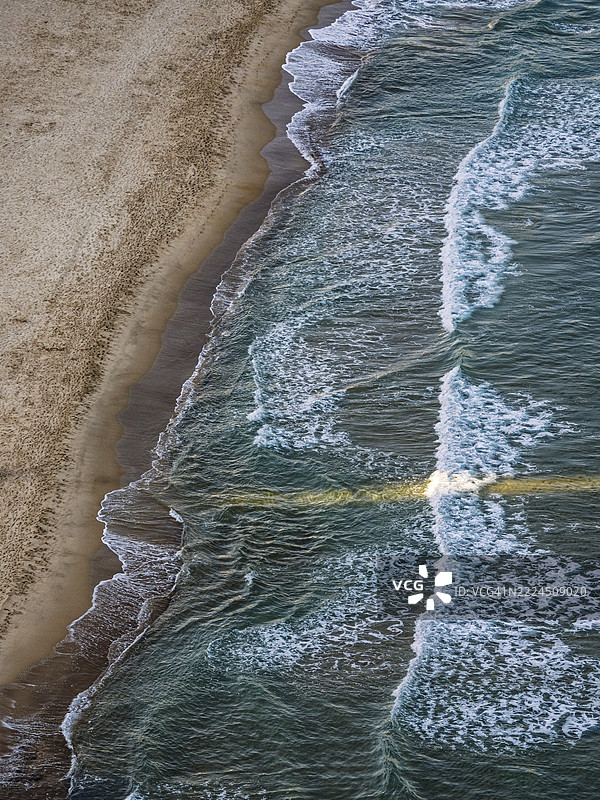 海岸地区的鸟瞰图，拥有一片宽阔的沙滩和细小的波浪。图片素材