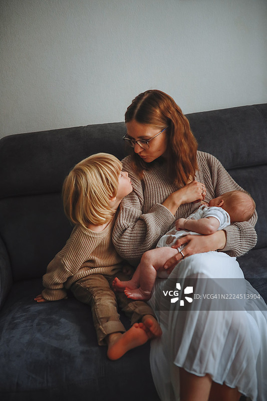 深色调的家庭时刻：感人的母乳喂养和拥抱场景图片素材