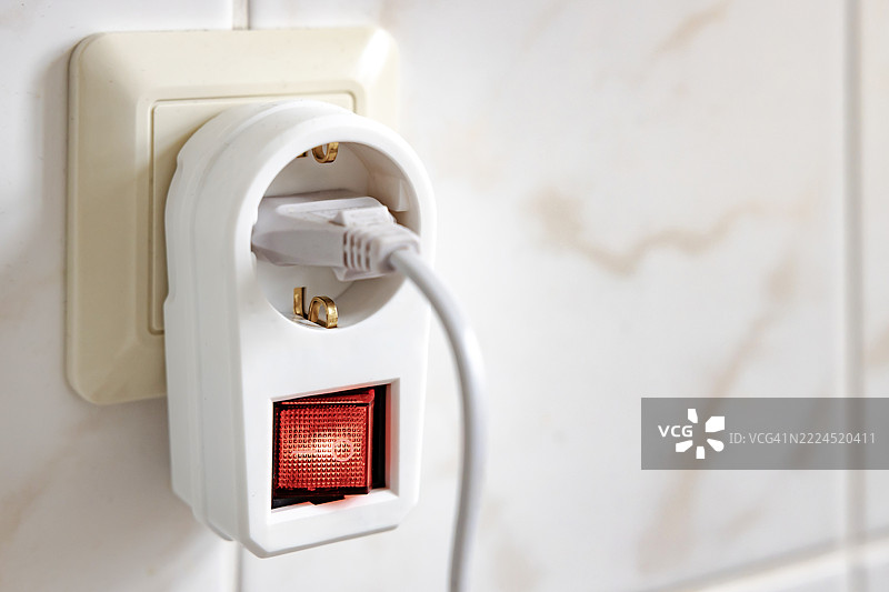 浴室瓷砖上的插座与插头之间的中间电源开关图片素材