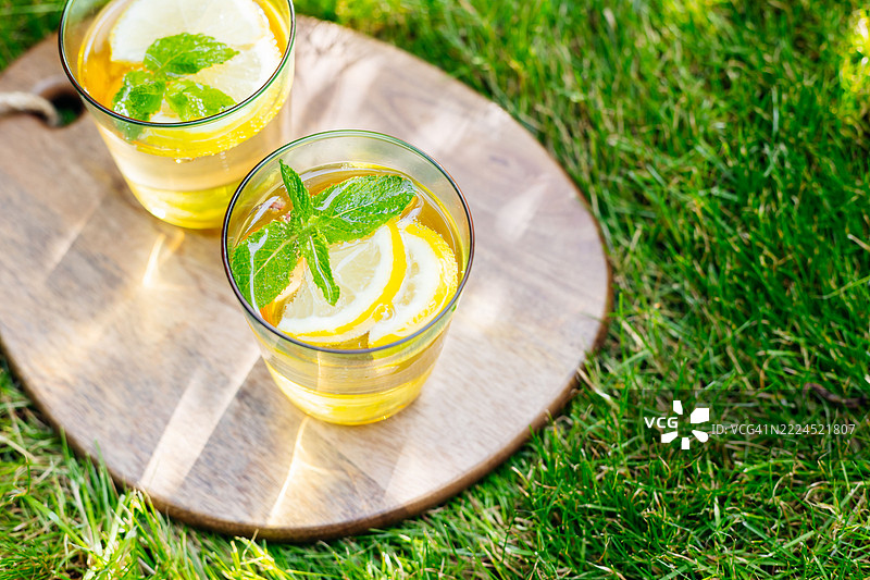 户外木质切菜板托盘上的柠檬水。夏季清爽饮品。冷却的柠檬薄荷排毒水。图片素材