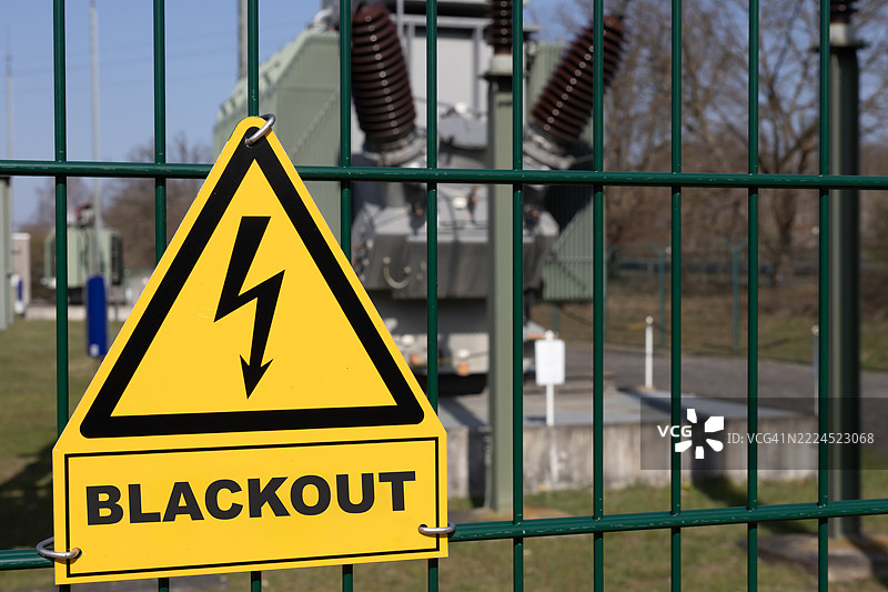 高压警告标志和背景中的“停电”字样，位于电力变压器站内图片素材