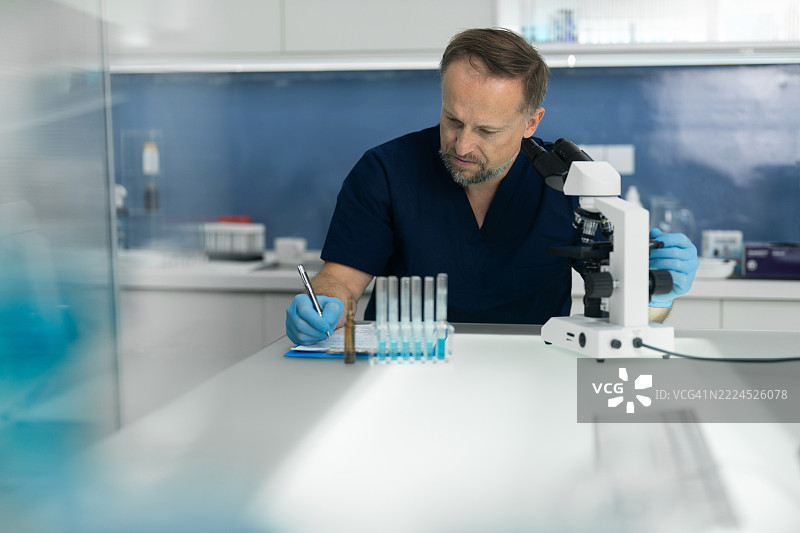 男性科学家在未来实验室工作，记录研究笔记。图片素材