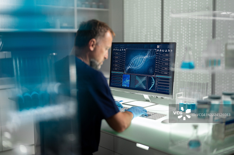 男性科学家在未来医学实验室工作。正在电脑屏幕上研究人类DNA。图片素材
