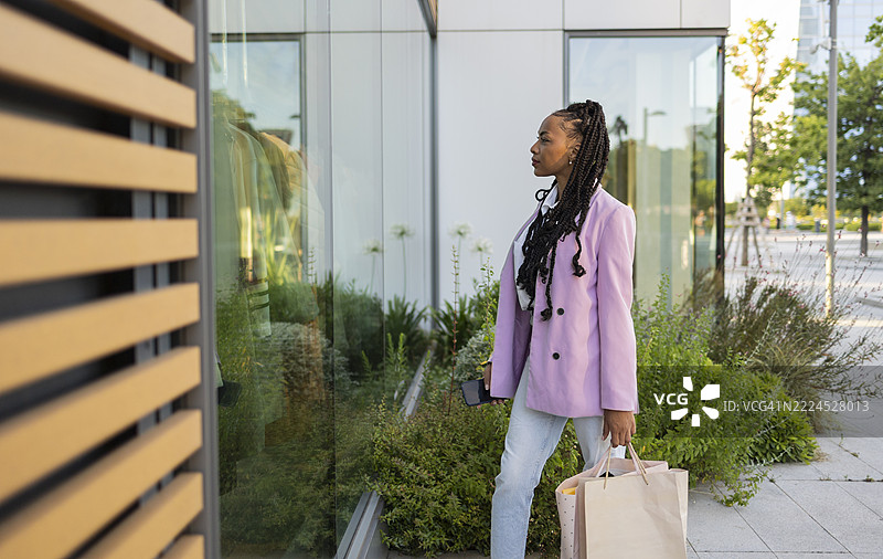 时尚年轻女性在街上走路时逛橱窗图片素材